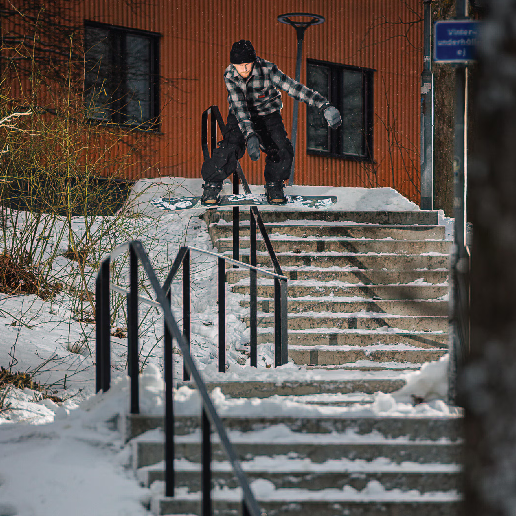 Armada Snowboards Tuffy with rider sliding down multi level staircase rail