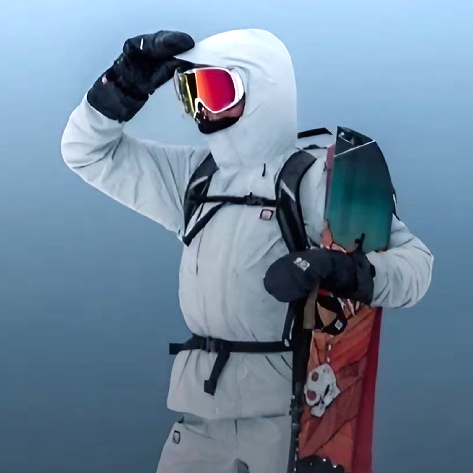 Bliz goggles on rider with hand holding jacket hood up with snowboard in arm