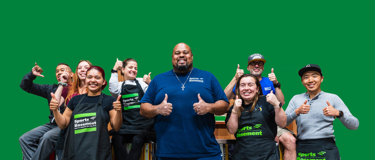 Group of people posing together with thumbs up against a green background