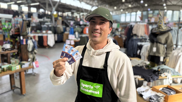Man holding a lift ticket discount cards in a store with 'Sports Basement' branding